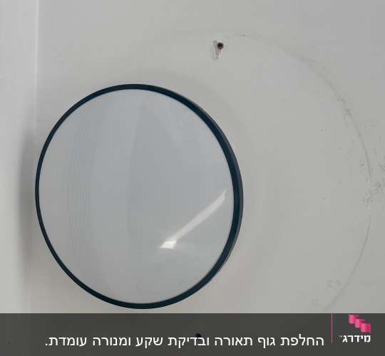 מנורה עגולה מותקנת על קיר לבן